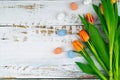 Multicolor Easter painted speckled eggs in basket on white wooden table with tulips. Traditional Spring composition Royalty Free Stock Photo