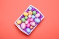 Multicolor eggs in a white tray. Creative Easter concept. Modern solid pink background. . Living coral theme - color of the year Royalty Free Stock Photo