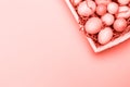 Multicolor eggs in a white tray. Creative Easter concept. Modern solid pink background. . Living coral theme - color of the year Royalty Free Stock Photo