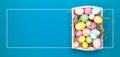 Multicolor eggs in a white tray. Creative Easter concept. Modern solid turquoise background.