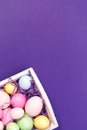 Multicolor eggs in a white tray. Creative Easter concept. Modern solid ultra violet background