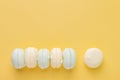 Multicolor marshmallows zephyr in a row on pastel yellow background