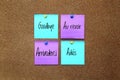 Multicolor notes with important message, motivation and reminders on cork board `Goodbye` in different languages: English, French, Royalty Free Stock Photo
