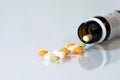 Multicolor pills and bottle on bright background, glass table and reflection