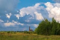 Multicolor rainbow on the background of a beautiful cloudy sky and a red church with a bell tower Royalty Free Stock Photo