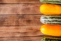 Multicolored assorted zucchini on a wooden table. The view from the top. Space for text