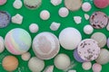 Multicolored bath bombs on a green background, top view.