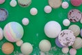 Multicolored bath bombs on a green background, top view.