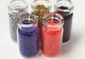 Multicolored beads in glass jars. Beads are poured on a white background. Plastic multi-colored polymers. Plastic pillets Royalty Free Stock Photo