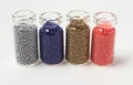 Multicolored beads in glass jars. Beads are poured on a white background. Plastic multi-colored polymers. Plastic pillets Royalty Free Stock Photo