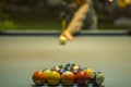 A multicolored billiard balls lie in the shape of a triangular pyramid on the blue cloth of the table against the background of a