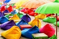 Multicolored bright beach umbrellas, ottomans and tables in the beach cafe. Summer multicolored background. Royalty Free Stock Photo