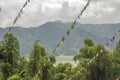 A multicolored Buddhist Tibetan prayer flags against the green forest of a lake and mountains Royalty Free Stock Photo