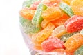 Multicolored candied fruits in a glass jar on a light background