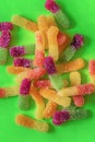 Multicolored candy gummy worms scattered on a green background