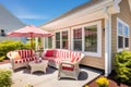 a multicolored cape cod with sizable porch housing patio furniture