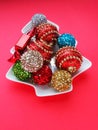 Multicolored Christmas balls on a white plate in the form of a Christmas tree. Christmas tree. Red background or crimson