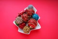 Multicolored Christmas balls on a white plate in the form of a Christmas tree. Christmas tree. Red background or crimson