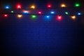 Multicolored christmas lights on a blue brick wall background. Colorful background for new years design. Merry christmas greeting Royalty Free Stock Photo