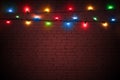 Multicolored christmas lights on brown brick wall background. Colorful background for new year design. Merry Christmas greeting ca Royalty Free Stock Photo