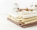 Multicolored clean towels with a branch of cotton on a light wooden background with copy space. Texture of cotton, waffle towel, t