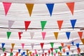 Multicolored colorful triangles bunting paper cut hanging on white thread under fabric roof at street night market