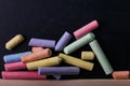 Multicolored crayons lie on a black chalkboard, copy space, macro. The concept of school, education and childhood Royalty Free Stock Photo