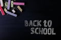 Multicolored crayons lie on a black chalkboard, copy space. The concept of school, education and childhood Royalty Free Stock Photo