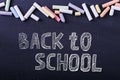 Multicolored crayons lie on a black chalkboard, copy space. The concept of school, education and childhood Royalty Free Stock Photo