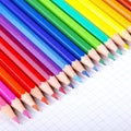 Multicolored crayons on white squared paper background.