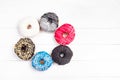 Multicolored decorated doughnuts laying on white wooden background. Sweet donuts on the table.