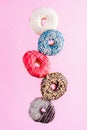 Multicolored decorated doughnuts in motion falling on pink background. Sweet doughnuts flying in motion. Royalty Free Stock Photo