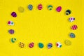 Multicolored decorative small Easter eggs laid out in oval on yellow background. Top view, flat lay.  Easter postcard, copy space Royalty Free Stock Photo