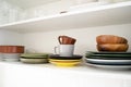 Multicolored dishes on a shelf in a white kitchen cabinet. Royalty Free Stock Photo