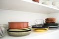 Multicolored dishes on a shelf in a white kitchen cabinet. Royalty Free Stock Photo