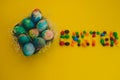 Multicolored Easter eggs lie in a basket on a yellow background, with bright colored sweets, close-up. Concept Easter and holiday Royalty Free Stock Photo