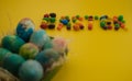Multicolored Easter eggs lie in a basket on a yellow background, with bright colored sweets, close-up. Concept Easter and holiday Royalty Free Stock Photo