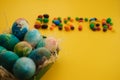 Multicolored Easter eggs lie in a basket on a yellow background, with bright colored sweets, close-up. Concept Easter and holiday Royalty Free Stock Photo
