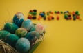 Multicolored Easter eggs lie in a basket on a yellow background, with bright colored sweets, close-up. Concept Easter and holiday Royalty Free Stock Photo