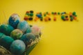 Multicolored Easter eggs lie in a basket on a yellow background, with bright colored sweets, close-up. Concept Easter and holiday Royalty Free Stock Photo