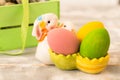 Multicolored Easter eggs in a wooden box, rabbit, ribbons on a wooden background. Country style.