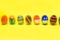 Multicolored Easter eggs on a yellow background with place for text. Patterns and designs on colored dyed eggs Royalty Free Stock Photo