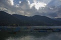 A multicolored empty wooden boats on the lake against the background of green mountains and evening sunset sky with clouds Royalty Free Stock Photo