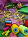 Multicolored fabrics and threads with scissors and needles closeup