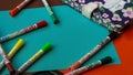 Multicolored felt-tip pens lie on colorful bright cardboard next to the notepad