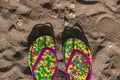 Multicolored flip flops on sand with drawn heart shape. Consept of vacation