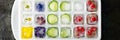 Multicolored frozen ice cubes with fruits, flowers and vegetables on a dark background