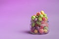 Multicolored fruit flavored popcorn in glass cups on pink background. Candy coated popcorn