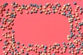 Multicolored glazed dragees are arranged in the form of a frame on a coral background. Royalty Free Stock Photo