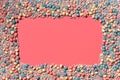 Multicolored glazed dragees are arranged in the form of a frame on a coral background. Royalty Free Stock Photo
